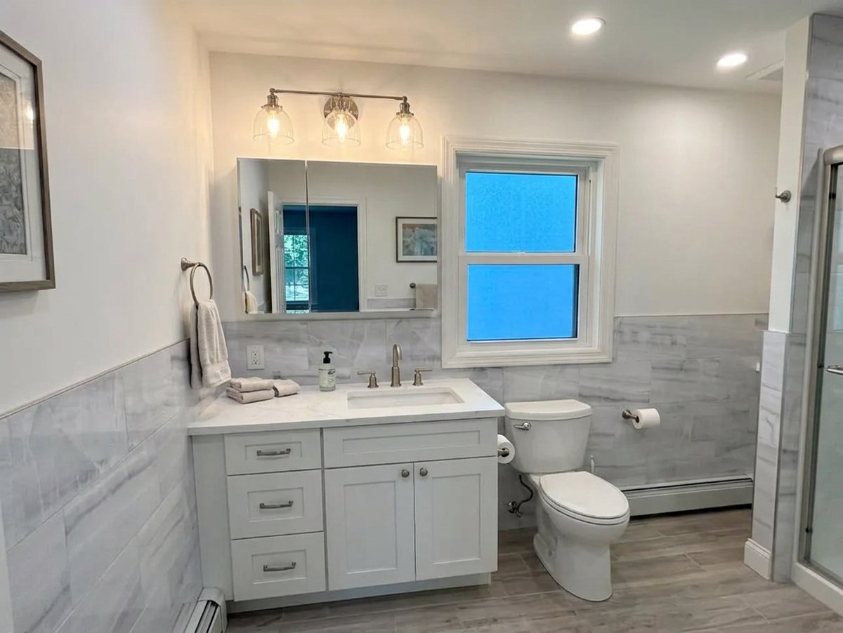 Bright white vanity and tile wainscot in a Long Island bathroom renovation - Best In Class Renovations