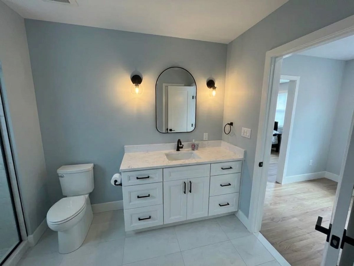 White bathroom vanity with arched mirror and sconces in Suffolk County NY - Best In Class Renovations